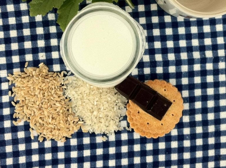 Сурово оризово мляко : Нова и подобрена рецепта 75 Веган Milker чаша мляко, кафяв ориз, бял ориз, шоколадови пръчици и бисквити върху синя и бяла карирана кърпа.
