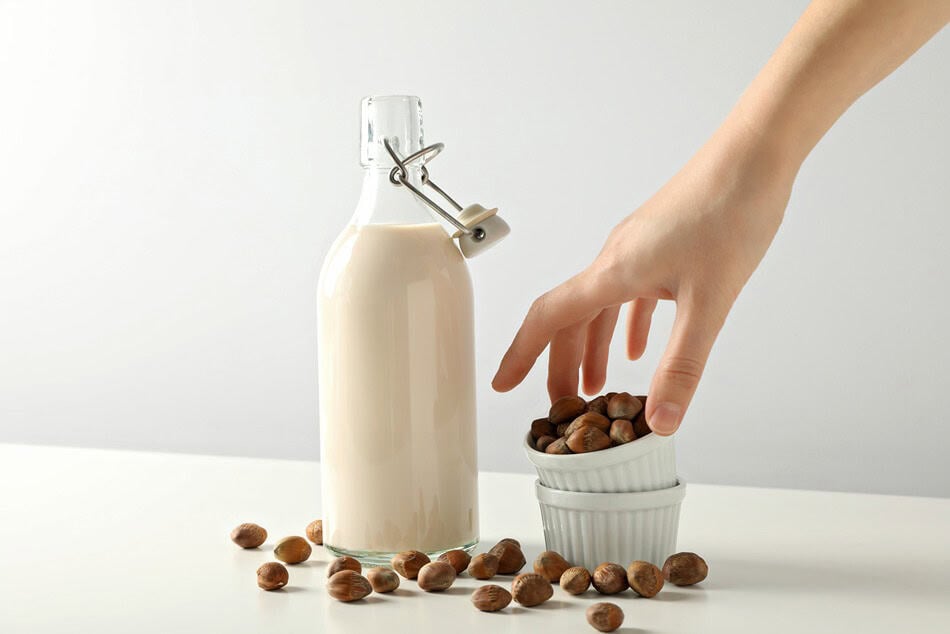 bottle with milk hand and bowls with nuts on whit 2025 03 25 08 07 42 utc